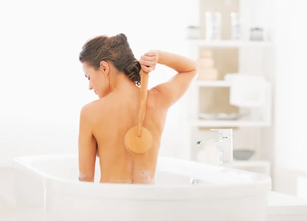 Junge Frau wäscht sich mit Körperbürste in Badewanne — Stockfoto