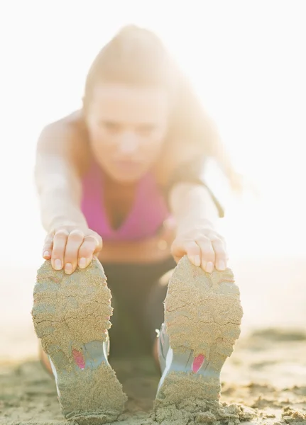 Detailní záběr na fitness mladá žena táhnoucí se na pláži — Stock fotografie