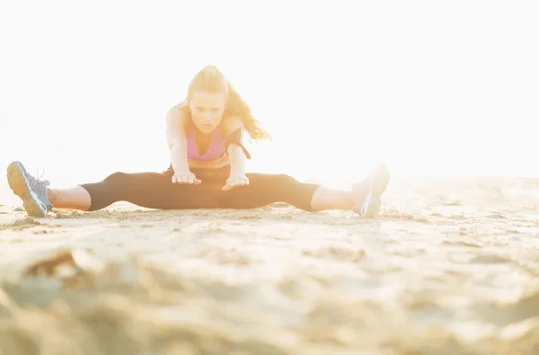 Fitness mladá žena táhnoucí se na pláži — Stock fotografie