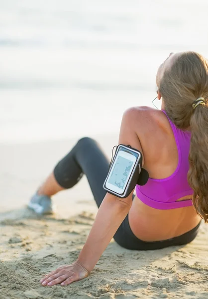 Fitness junge Frau sitzt am Strand. Rückansicht — Stockfoto