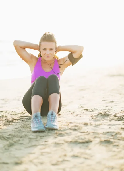 Fitness young woman doing abdominal crunch on beach — Stock Photo, Image