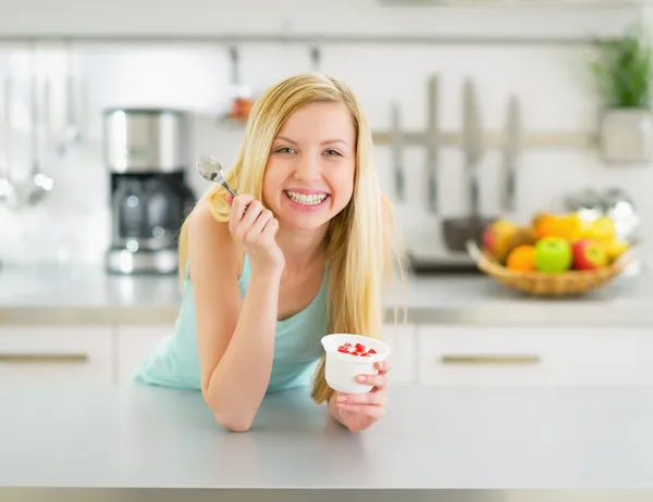 Mulher comendo iogurte na cozinha — Fotografia de Stock