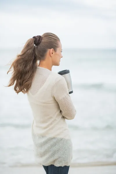 Woman on beach with hot beverage — Stock Photo, Image