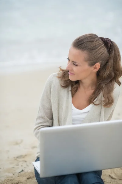 Femme assise avec ordinateur portable sur la plage — Photo