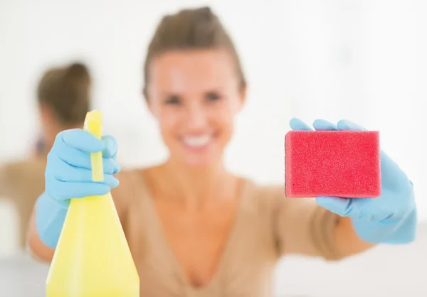 Housewife showing spray bottle and sponge — Stock Photo, Image