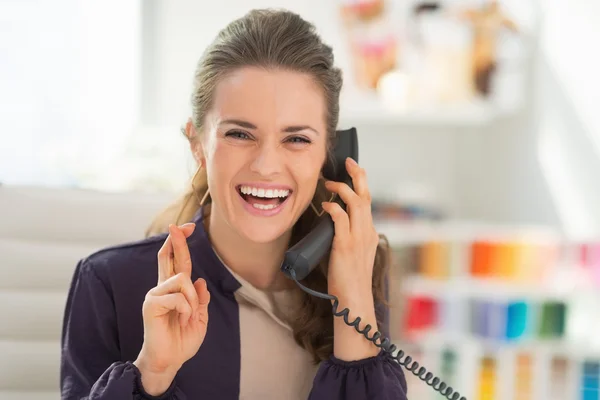 Designer talking phone with crossed fingers — Stock Photo, Image