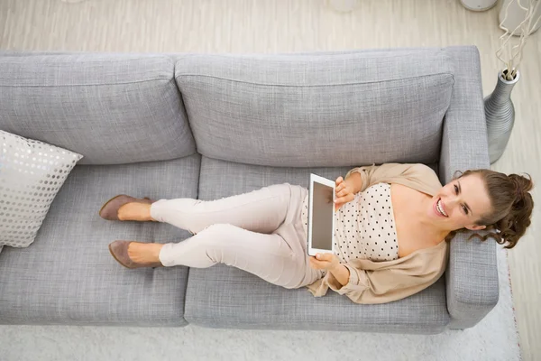 Mulher sorridente no sofá com tablet — Fotografia de Stock