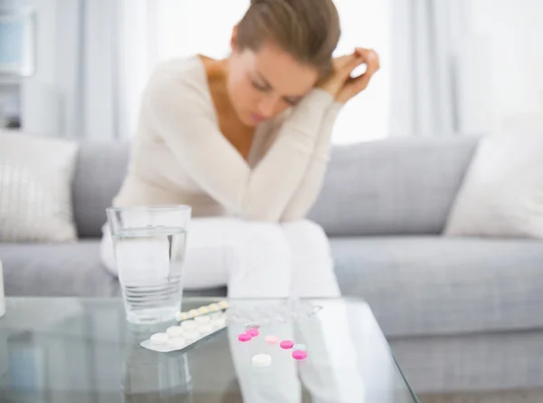 Pills on table and young woman — Stock Photo, Image