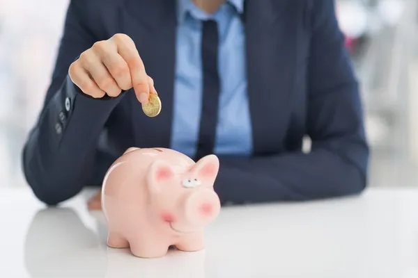 Business woman putting coin into piggy bank — Stock Photo, Image