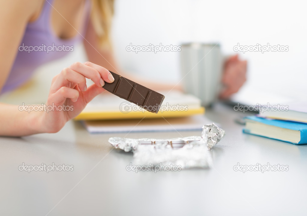 Teenager girl eating chocolate and studying