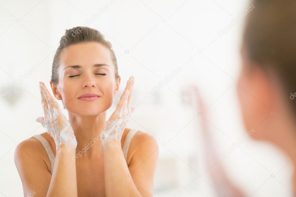 Woman washing face in bathroom