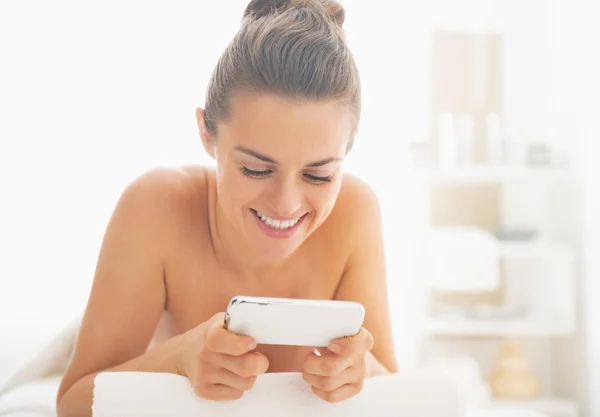 Woman on massage table and writing sms — Stock Photo, Image