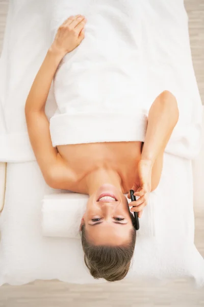 Woman on massage table talking phone — Stock Photo, Image