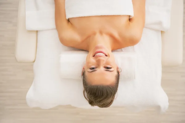 Mulher feliz que põe na mesa de massagem — Fotografia de Stock