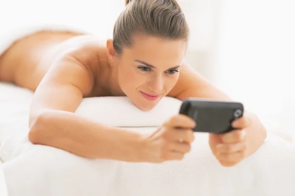 Frau auf Massagetisch schreibt SMS — Stockfoto