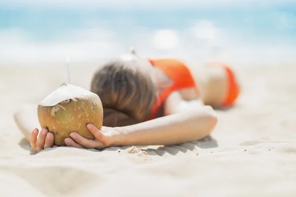 Молодая женщина с кокосом отдыхает на пляже — стоковое фото