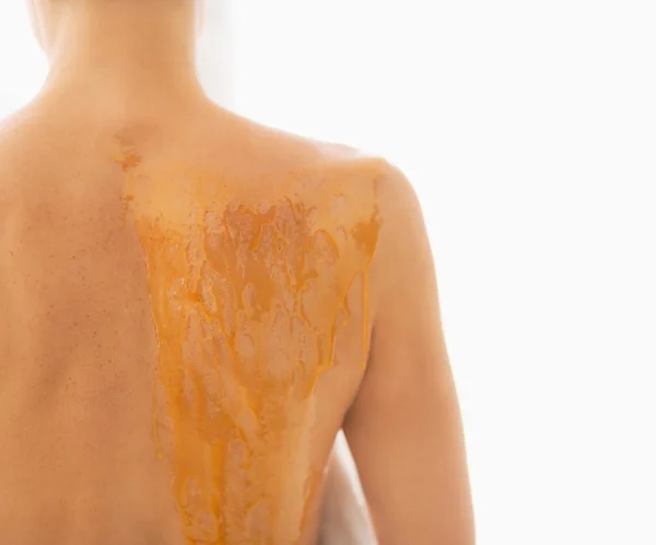 Nahaufnahme einer jungen Frau, deren Rücken mit Honig beschmiert ist. Rückansicht — Stockfoto