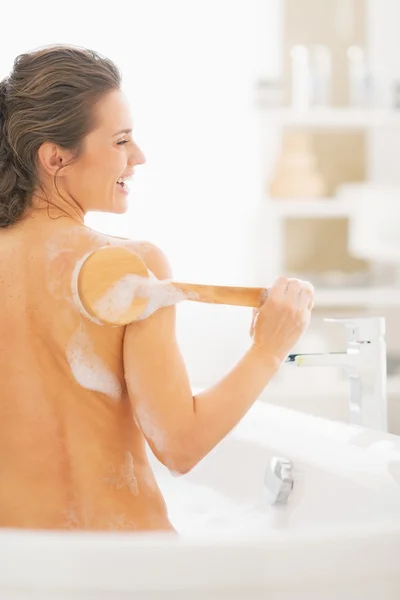 Mujer en bañera usando cepillo corporal — Foto de Stock