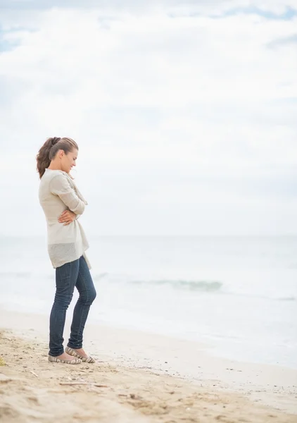 Thoughtful woman standing on cold beach — Stock Photo, Image