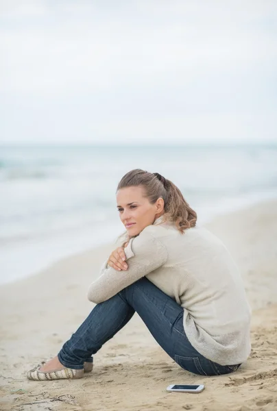 Rustige vrouw zittend op koude strand — Stockfoto