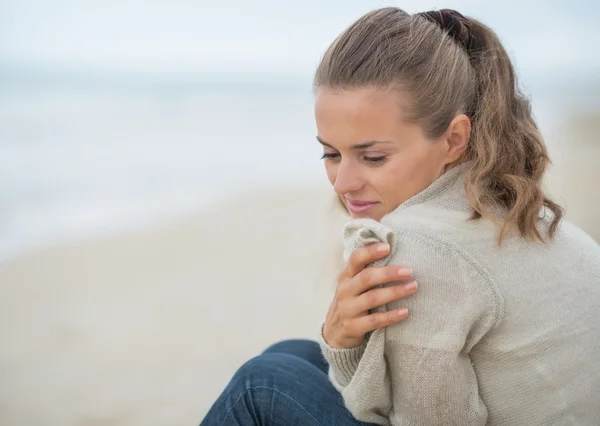 Frau sitzt am kalten Strand — Stockfoto
