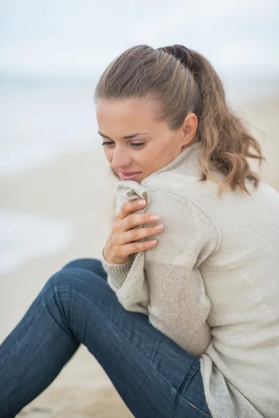 Vrouw zittend op koude strand — Stockfoto
