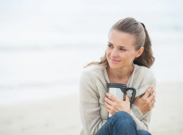 Woman on beach with hot beverage — Stock Photo, Image