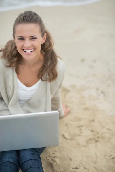 Happy woman sitting with laptop on beach — Stock Photo, Image