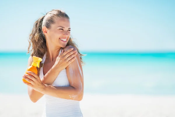 Femme sur la plage appliquant crème solaire — Photo