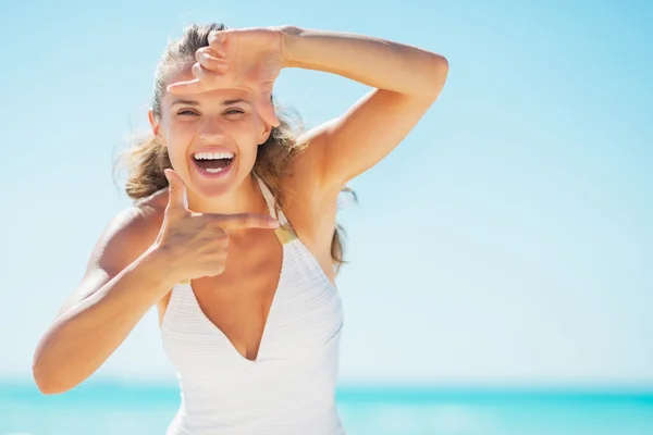 Lachende vrouw op strand framing met handen — Stockfoto