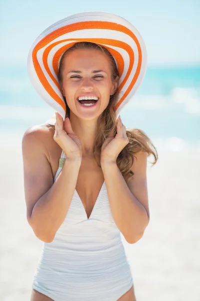 Glimlachende jonge vrouw met hoed op strand — Stockfoto
