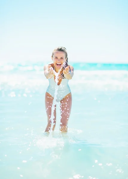 Mujer sonriente en la playa jugando con agua — Foto de Stock