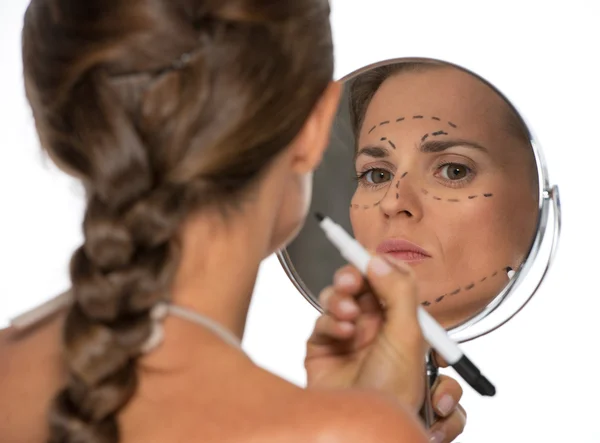 Kvinna som tittar i spegeln och plastikkirurgi varumärken — Stockfoto