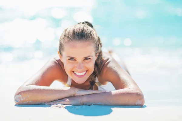 Smiling young woman laying at seaside — Stock Photo, Image