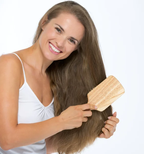 Sonriente joven peinando el cabello — Foto de Stock