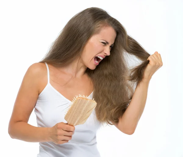 Stressed young woman combing hair — Stock Photo, Image