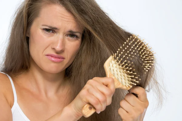 Frustrierte junge Frau kämmt Haare — Stockfoto