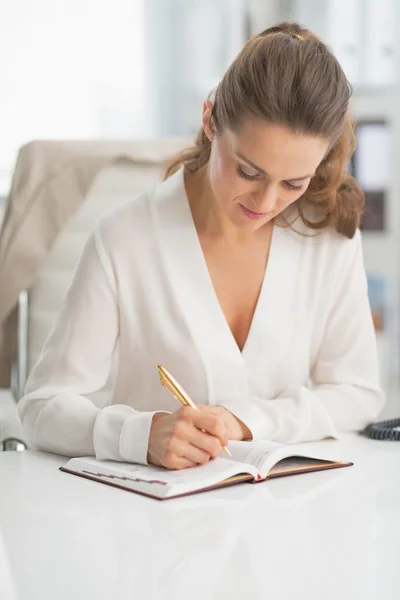 Business woman writing in notepad — Stock Photo, Image