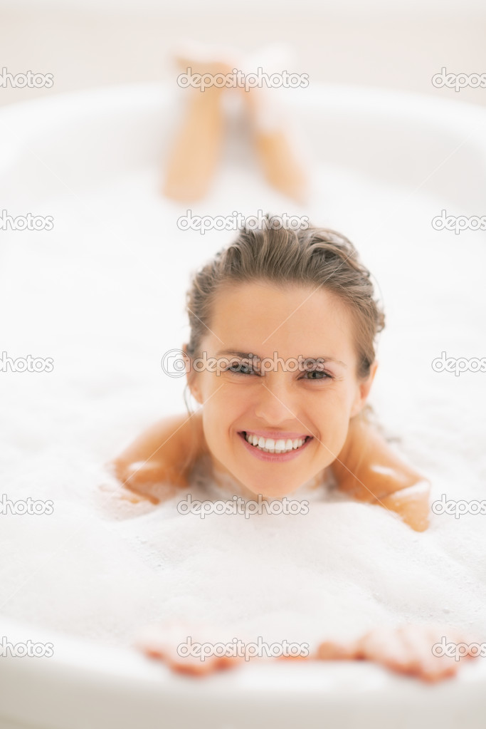 Smiling woman laying in bathtub
