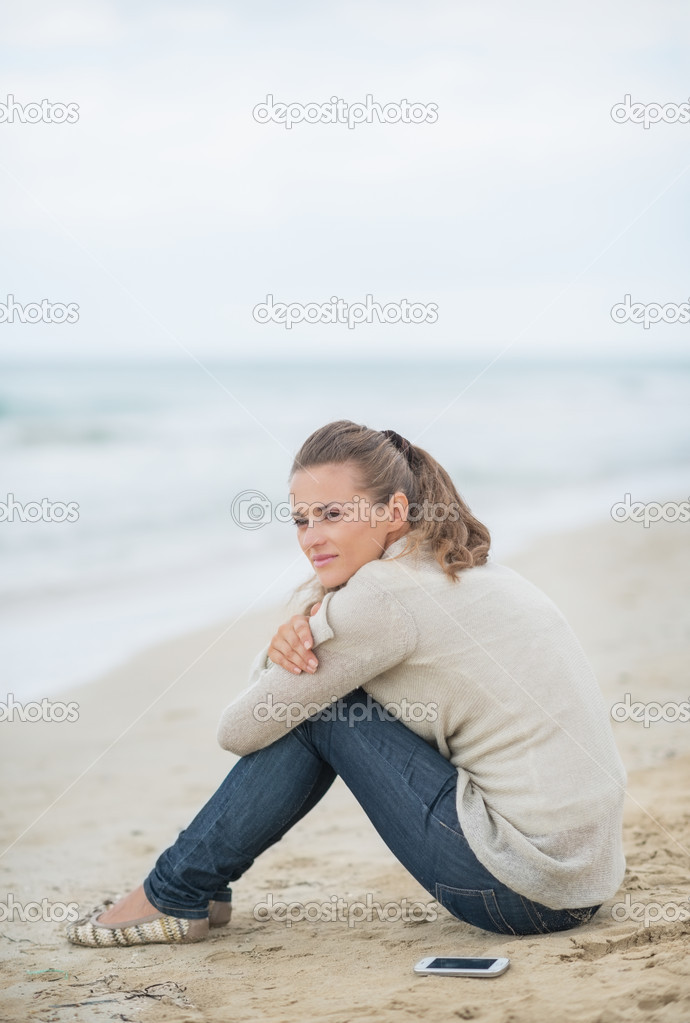 Calm woman sitting on cold beach