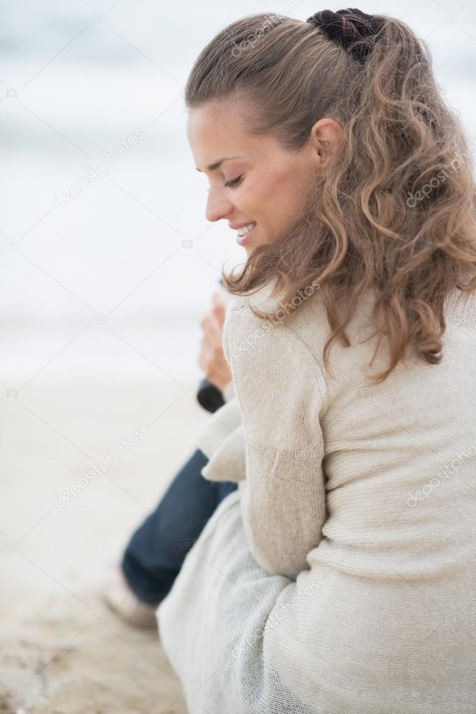 Happy woman sitting on cold beach