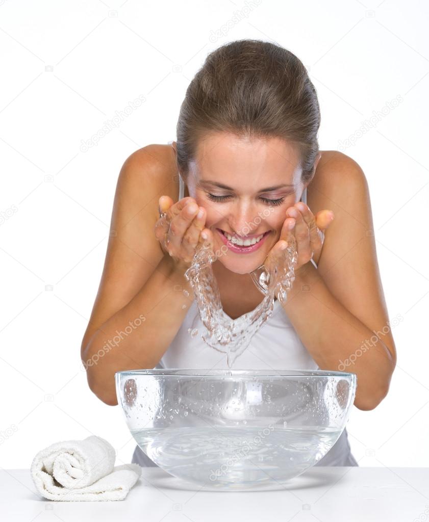 Happy young woman washing face