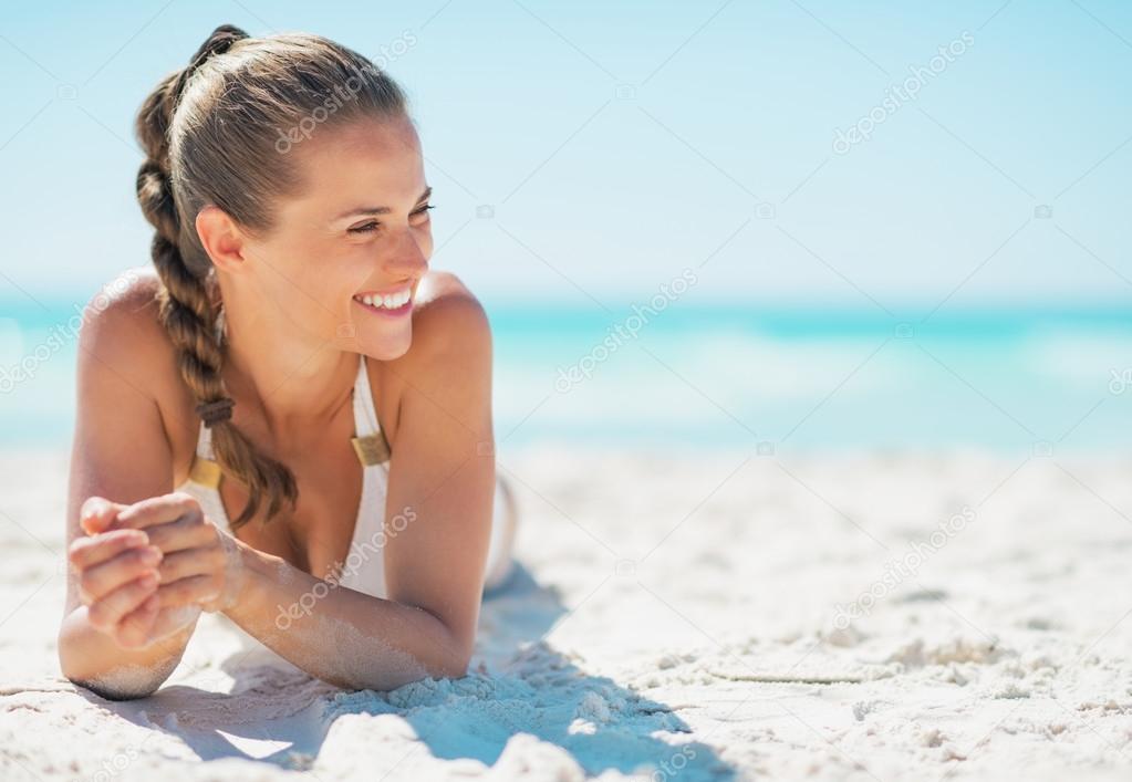 Happy young woman laying on beach