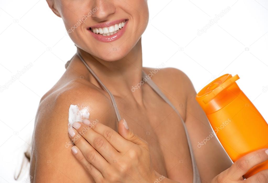 Young woman applying sun screen bottle