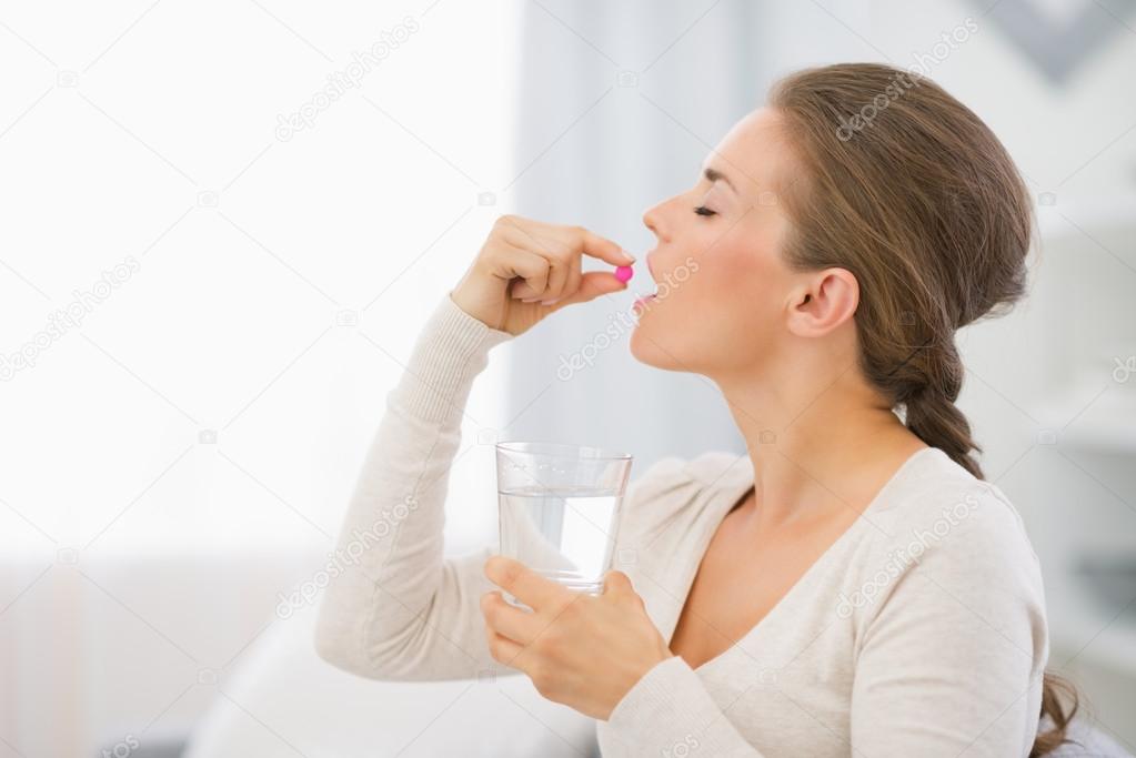 Happy young woman taking pill