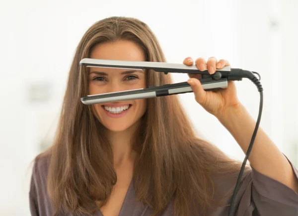 Woman looking through hair straightener — Stock Photo, Image