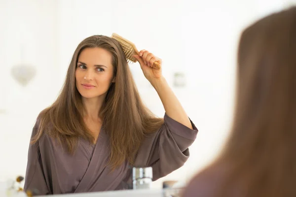 Mulher pentear o cabelo no banheiro — Fotografia de Stock