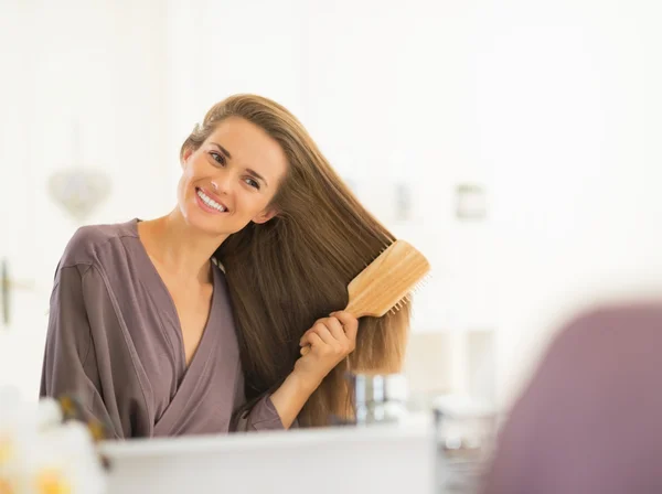 Mulher pentear o cabelo no banheiro — Fotografia de Stock