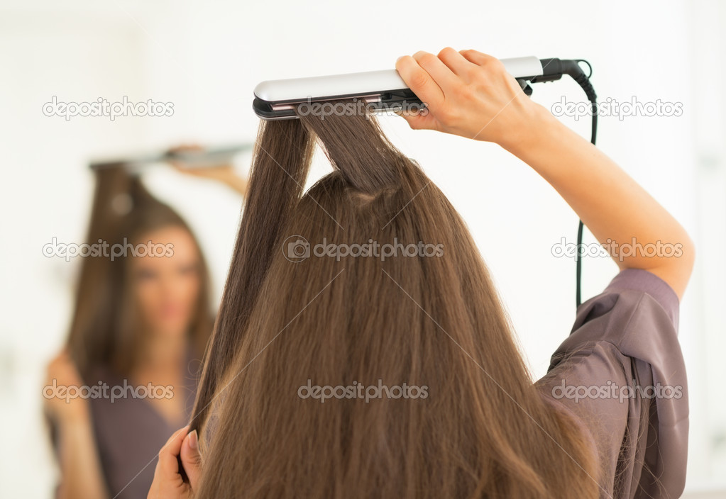 Woman using hair straightener