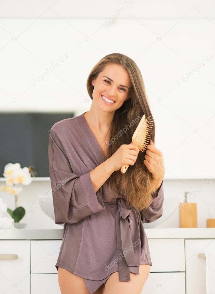Woman combing hair in bathroom